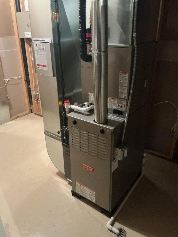 Completed full HVAC system installation including furnace, air conditioning unit, and humidifier in residential basement location. Installed new beige furnace unit with proper venting and connected to existing ductwork infrastructure. Mounted indoor air handler section compatible with R-410A refrigerant specifications and integrated leak detection system as required by manufacturer guidelines. Configured silver galvanized steel ductwork and plenum chambers to ensure optimal airflow distribution throughout the residence. Installed white PVC condensate drainage lines with secure mounting brackets to prevent water damage. Connected all electrical components to circuit breaker panel following local electrical codes. Verified all manufacturer labels, specification plates, and safety warnings are clearly visible and accessible for future service needs. System tested and confirmed operational.