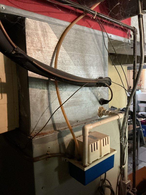 Performed AC service call on R-22 system with history of no cooling issues, last serviced in 2018. Inspected outdoor condenser unit and indoor air handler in basement installation. Evaluated system performance and identified aging refrigerant system as potential concern for future reliability. Documented equipment condition with photos of exterior condenser location and indoor air handling unit with associated refrigerant lines and electrical connections.