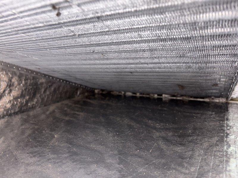 Responded to a warranty callback for water leak underneath furnace unit following recent GFCI replacement. Upon inspection, discovered water accumulation beneath the air handler with visible moisture and debris buildup at component seams and heat exchanger surfaces. Documented conditions with photos showing the affected areas including the corrugated heat exchanger fins and junction points where water infiltration occurred.