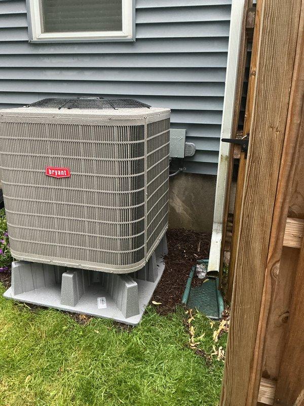Completed installation of Bryant heat pump system including indoor air handler and outdoor condensing unit. Indoor equipment installed in basement with proper ductwork connections and outdoor unit positioned on composite pad against exterior wall with electrical disconnect. Initial installation completed but startup procedures postponed due to inclement weather conditions; scheduled return visit to perform system startup, testing, and final commissioning.