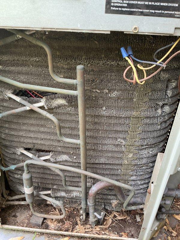 Completed AC tune-up and membership renewal service for system transitioning from heat-only to full heating and cooling operation. Outdoor condenser unit inspected and documented showing significant accumulation of dust, debris, and lint between coil fins requiring attention. Unit operational with all safety labels and electrical components intact; service rescheduled for additional maintenance work.