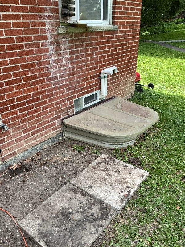 Completed installation of Bryant air conditioning system with outdoor condensing unit positioned on concrete pad against brick exterior wall. Unit was properly mounted, refrigerant lines were run vertically along brick wall with secure mounting brackets, electrical disconnect box was installed, and system was charged and tested using manifold gauges to verify proper refrigerant pressures and operational performance.