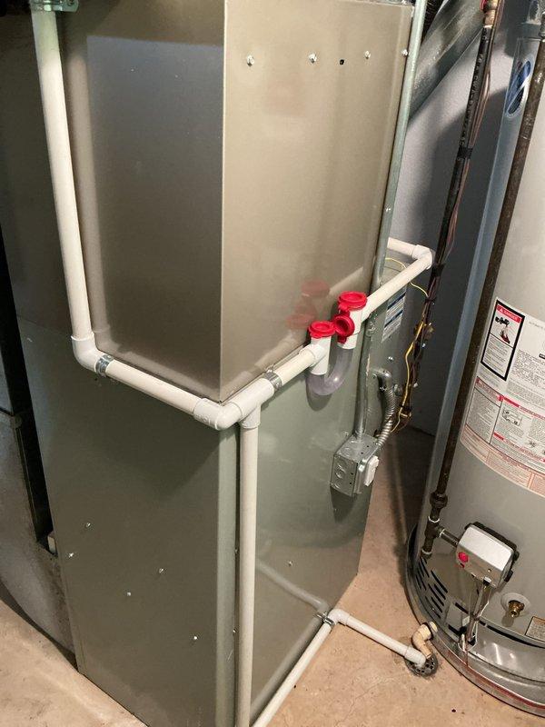 Completed installation of new air conditioning system with evaporator coil in residential mechanical room. Installed air handler unit with proper condensate drainage system utilizing white PVC piping with appropriate caps and connections. System was tested for proper operation, and installation was reviewed with homeowner upon completion to ensure full understanding of the new equipment.