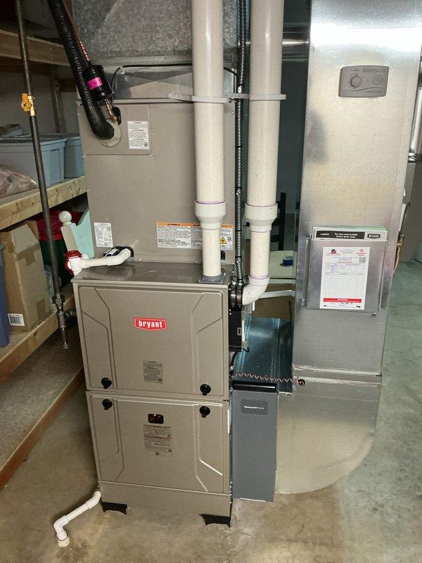 Completed full HVAC system installation in residential basement utility room, including new Bryant furnace unit and associated components. Installed vertical PVC venting system with proper support brackets and metal strapping, routed black flexible ductwork, and integrated electrical disconnect box with proper labeling. Configured condensate drain line with PVC piping, elbow joints, and drain pan with secure metal clamps and support brackets mounted to concrete floor. All components properly mounted, leveled, and secured per manufacturer specifications and building codes. System tested and verified operational upon completion.