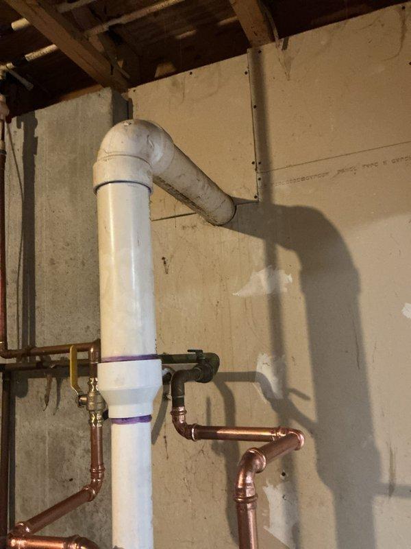 Completed installation of 50-gallon power vent water heater in basement utility area. Installed new copper supply piping with shut-off valves, configured proper venting system using white PVC pipe with 90-degree elbow transition from vertical to horizontal run, and mounted power vent motor assembly on top of unit. All connections tested and verified operational, with customer payment processed via credit card.