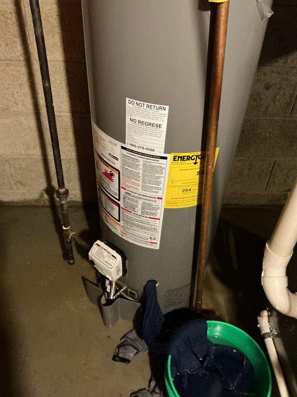 Responded to after-hours emergency call for leaking water heater. Upon arrival, found tanked water heater with active leak and visible corrosion on piping connections. Assessed unit condition, documented damage with photos, and placed collection bucket to contain water discharge. Identified compromised fittings and aging copper pipe connections requiring repair to restore system integrity.