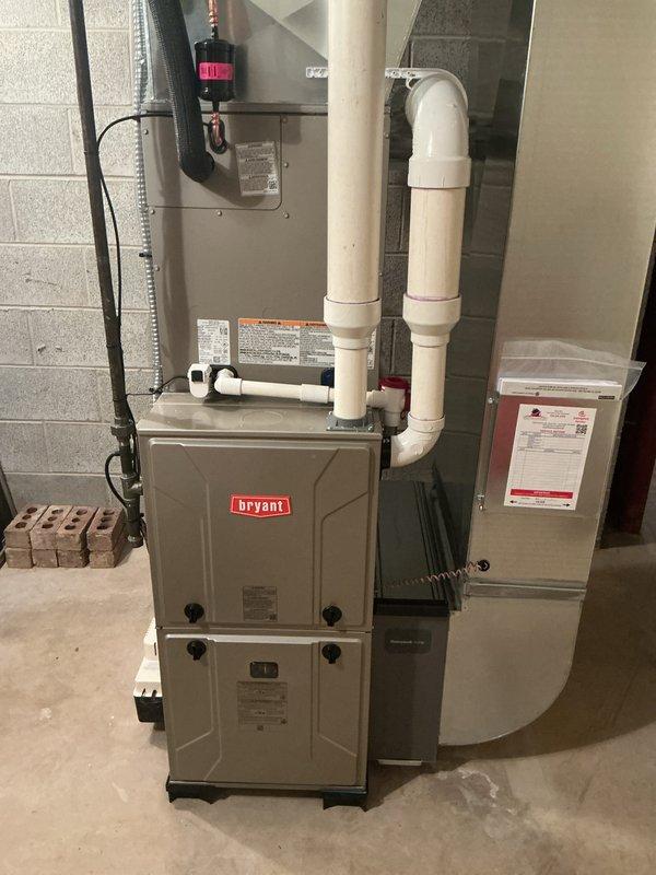 Completed full HVAC system installation consisting of two Bryant furnaces with corresponding air conditioning units and humidifiers in residential property. Indoor equipment installed in basement utility area on concrete pad with proper venting via PVC exhaust and intake piping routed through exterior wall. Outdoor condensing units positioned on concrete pads with appropriate clearances and secured refrigerant line connections. All equipment commissioned, tested for proper operation, and left in fully functional condition with manufacturer specifications verified.