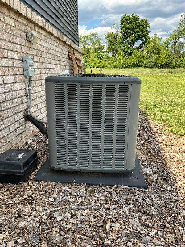 Responded to service call for unlevel outdoor AC unit. Upon arrival, inspected condenser unit positioned on black composite pad against exterior wall. Confirmed unit was operational but sitting unevenly on pad foundation. Assessed installation pad placement and verified unit stability. Documented current conditions with photos showing unit positioning on mulch bed with proper clearances maintained. Provided customer with quote for leveling and pad adjustment services to ensure proper drainage and equipment longevity.