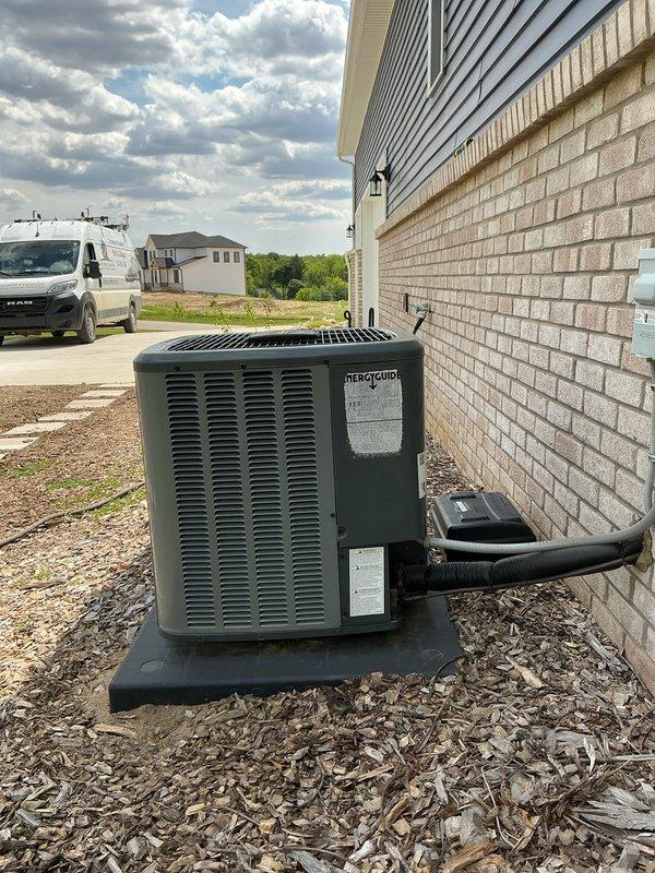 Responded to service call for unlevel outdoor AC unit. Upon arrival, inspected condenser unit positioned on black composite pad against exterior wall. Confirmed unit was operational but sitting unevenly on pad foundation. Assessed installation pad placement and verified unit stability. Documented current conditions with photos showing unit positioning on mulch bed with proper clearances maintained. Provided customer with quote for leveling and pad adjustment services to ensure proper drainage and equipment longevity.