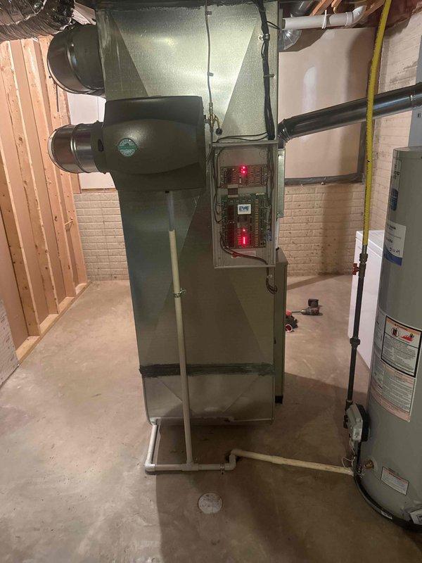 Completed full HVAC system installation in residential basement utility room, including new gas furnace with proper venting and ductwork connections, air handler with flexible metal ducting distribution, and integrated water heater. All equipment properly mounted with appropriate clearances, gas line connections secured, electrical components wired to panel with indicator lights operational, and system tested for safe operation. Installation meets code requirements with organized routing of all ductwork, piping, and conduits throughout the mechanical space.
