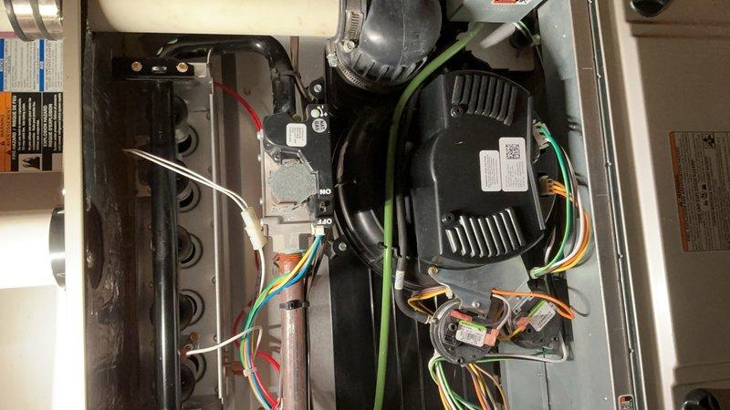 Responded to service call for thermostat malfunction displaying code 33 (limit fault) preventing complete system shutdown. Diagnosed faulty limit switch causing blower motor to run continuously. Performed AC tune-up including inspection of blower assembly, gas valve connections, and electrical wiring harness. Verified proper operation of all colored wire connections to control board and motor assembly. Documented internal components and wiring configuration with photographs showing blower motor, gas valve, and control systems in operational condition.