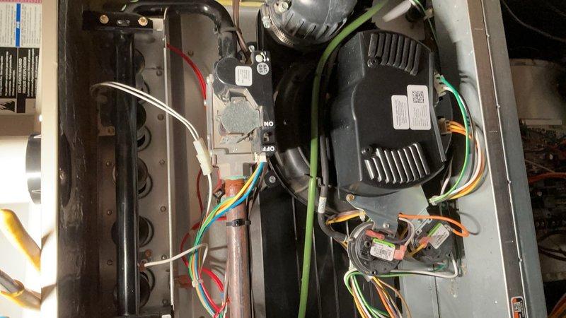 Responded to service call for thermostat malfunction displaying code 33 (limit fault) preventing complete system shutdown. Diagnosed faulty limit switch causing blower motor to run continuously. Performed AC tune-up including inspection of blower assembly, gas valve connections, and electrical wiring harness. Verified proper operation of all colored wire connections to control board and motor assembly. Documented internal components and wiring configuration with photographs showing blower motor, gas valve, and control systems in operational condition.