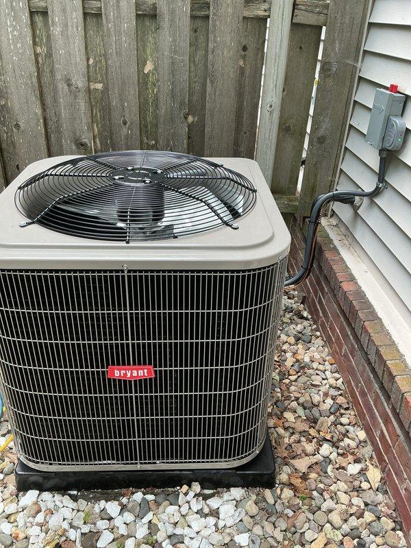 Completed installation of new Bryant air conditioning system including outdoor condenser unit and indoor evaporator coil. Mounted condenser unit on composite pad with gravel base against exterior wall, installed electrical disconnect box on vinyl siding, and ran electrical conduit to unit. Interior installation included evaporator coil with new ductwork connections in mechanical closet, featuring galvanized supply plenum and metal elbow transitions integrated with existing system. Verified all refrigerant line connections, tested electrical components, and confirmed proper airflow through system. Unit positioned for optimal clearance and serviceability with secure mounting and professional finish work.