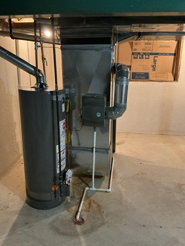 Responded to no cooling complaint at residential property. Upon arrival, inspected HVAC system located in basement utility area. Evaluated air conditioning unit and associated ductwork system. Documented existing conditions including water heater proximity to HVAC components and basement storage configuration affecting system accessibility. Verified ductwork connections and assessed airflow pathways through black PVC and metal duct components. Coordinated with property representative regarding necessary repairs to restore proper cooling function.