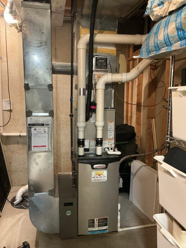 Completed installation of new Bryant air conditioning condenser unit and evaporator coil system. Modified basement mechanical room venting by raising power vent hot water tank exhaust piping above the outdoor condenser location using 3" PVC pipe and two 90-degree elbows to ensure proper clearance and code compliance. Installed heat dissipation board to protect adjacent equipment and optimize system performance.