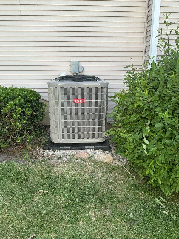 Completed installation of new Bryant air conditioning condenser unit and evaporator coil system. Modified basement mechanical room venting by raising power vent hot water tank exhaust piping above the outdoor condenser location using 3" PVC pipe and two 90-degree elbows to ensure proper clearance and code compliance. Installed heat dissipation board to protect adjacent equipment and optimize system performance.