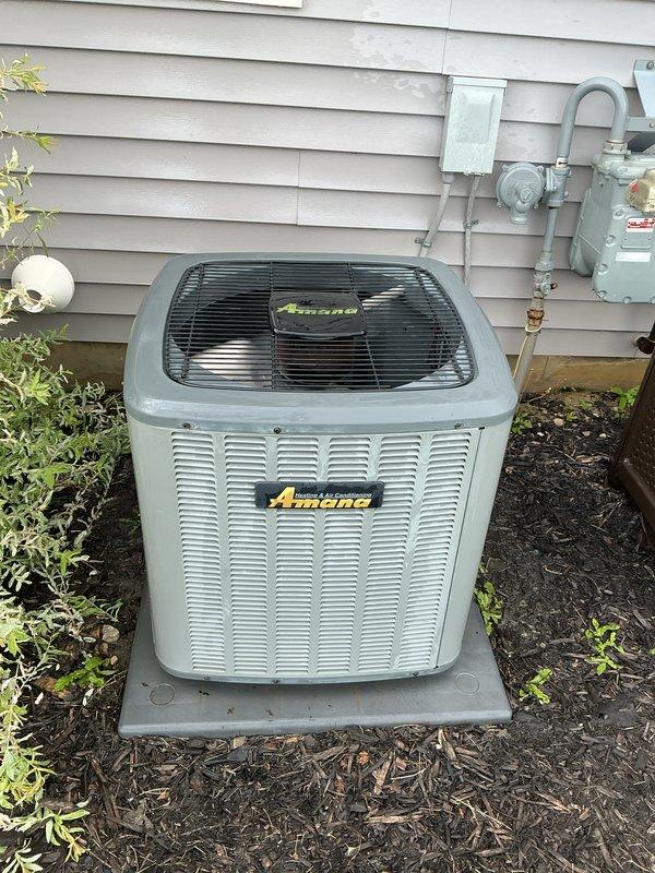 Completed spring air conditioning tune-up on an eight-year-old Amana condensing unit with no reported issues or symptoms. Performed comprehensive system inspection including examination of outdoor condenser components, electrical connections, and indoor furnace unit to ensure proper operation. Reviewed system performance with homeowner and documented equipment condition through photographs showing normal operating status of all components.