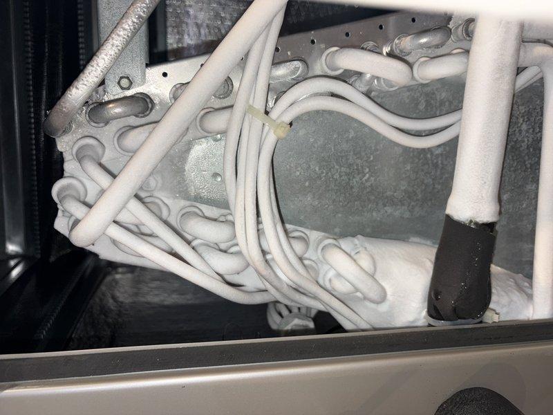 Responded to customer report of water leakage from AC unit. Upon arrival, observed water appearing to originate from condensation drainage system with visible pooling inside the unit cabinet. Opened service access panel and inspected interior components, including evaporator coil assembly and drain pan. Photographed exterior condensate drain line configuration showing PVC piping and corrugated drainage tubing at ground level. Documented interior refrigerant line routing and evaporator coil condition. Initial diagnostic inspection completed to identify source of water accumulation within unit housing.