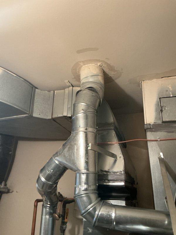 Completed full HVAC system installation including new air handler unit, ductwork routing with proper ceiling penetration and sealing, and associated copper refrigerant lines. All equipment mounted securely in mechanical room with proper clearances, ductwork transitioned through ceiling with galvanized metal components and sealed flanges, and plumbing connections established per manufacturer specifications.