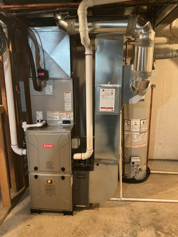 # HVAC Install - Complete System

Completed full residential HVAC system installation in basement mechanical room, including new Bryant furnace, air conditioning system, and whole-home humidifier. Installed all necessary ductwork transitions and metallic supply ducts with proper routing through floor joists. Connected white PVC condensate drain lines from furnace with appropriate trap configuration and drainage routing across floor to designated drain point. Verified all electrical connections, mounted control components on wall adjacent to furnace, and ensured proper clearances around equipment per manufacturer specifications. System tested and operational upon completion.