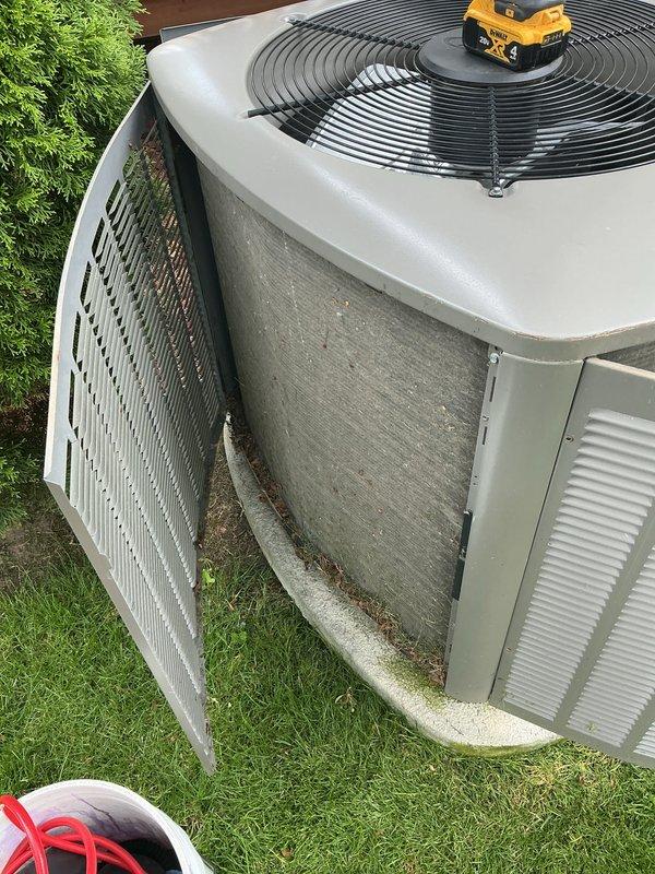 Performed comprehensive annual air conditioning tune-up and preventative maintenance on outdoor condenser unit. Accessed unit and discovered heavily soiled air filter and significant debris accumulation (leaves, twigs, pine needles, and organic matter) in coil channels and between heat exchanger fins. Cleaned condenser coils, removed all debris from unit interior and gaps, and replaced dirty filter to restore proper airflow and system efficiency.