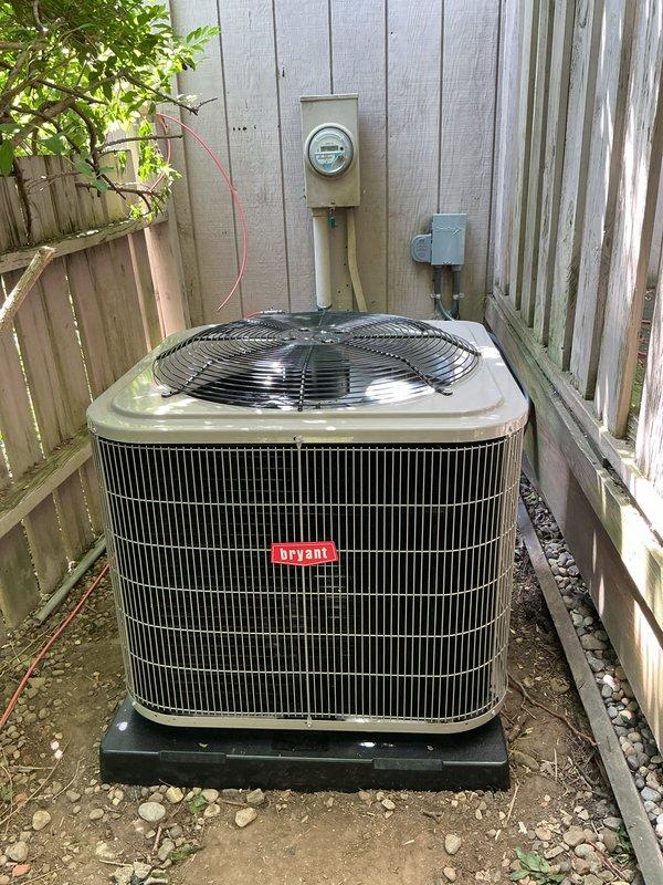 Completed installation of Bryant air conditioning condenser unit and associated ductwork system. Positioned outdoor condenser on protective pad against building exterior with proper electrical disconnect and metering connections, then installed galvanized metal ductwork sections with secure joints and clamps in the basement utility area to integrate with existing HVAC infrastructure.