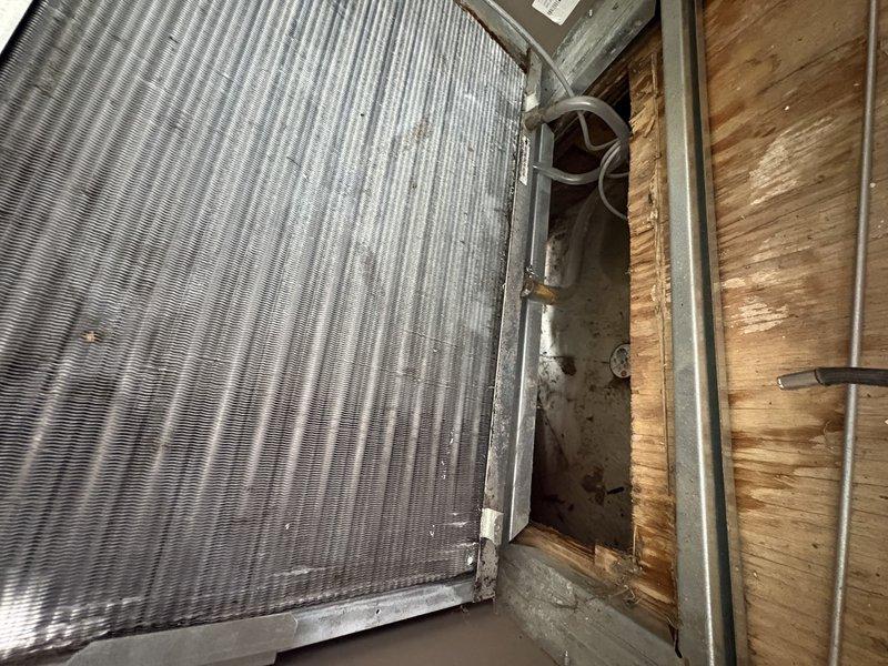 Responded to service call for reduced cooling performance on 5-year-old air conditioning system experiencing intermittent shutdowns during high ambient temperature conditions above 90 degrees. Performed comprehensive system inspection including evaporator coil examination in attic installation. Visual inspection revealed dust accumulation on coil fins and heat exchanger assembly, which can restrict airflow and reduce heat transfer efficiency. Documented coil condition with photographs showing vertical fin configuration and multi-row heat exchanger sections. Previous mold discovery on filter indicates potential moisture management issues contributing to reduced system performance. Completed annual maintenance including humidifier pad replacement as requested. System operational at time of departure but requires monitoring during peak cooling demand periods. Recommend follow-up evaluation of refrigerant charge, airflow measurements, and potential coil cleaning to address performance degr