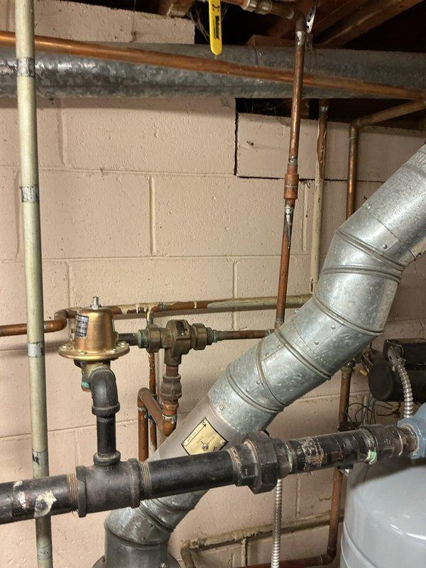 Responded to reported boiler leak in basement utility area. Upon arrival, performed thorough inspection of boiler system, pressure regulator assembly, expansion tank, and associated piping connections. Identified source of leak at valve assembly connected to expansion tank. Tightened fittings at brass valve connections and pressure relief valve. Inspected copper supply lines, black iron piping, and flexible hose connections for additional leak points. Verified proper operation of pressure regulator and gauge readings. Documented existing conditions of expansion tank and valve assembly with photographic evidence. System tested and confirmed no active leaking upon completion of repairs.