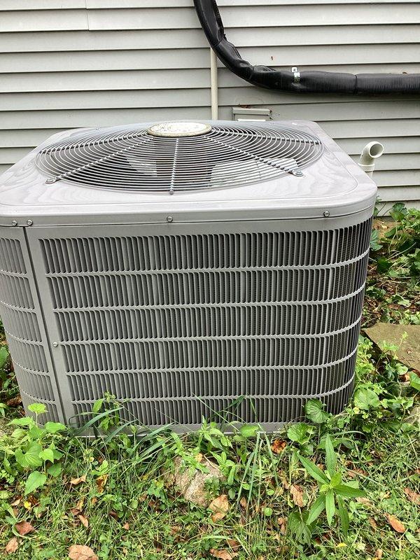 Performed annual AC tune-up on residential outdoor condenser unit. Completed standard maintenance inspection, verified operational status of compressor and fan motor, and documented equipment condition with photos. Unit found in satisfactory working order with normal outdoor weathering; vegetation around base noted but not obstructing airflow through coil fins.