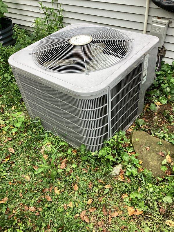 Performed annual AC tune-up on residential outdoor condenser unit. Completed standard maintenance inspection, verified operational status of compressor and fan motor, and documented equipment condition with photos. Unit found in satisfactory working order with normal outdoor weathering; vegetation around base noted but not obstructing airflow through coil fins.