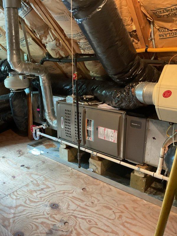 Completed full HVAC system installation including outdoor Bryant condensing unit and indoor air handler with evaporator coil. The outdoor condenser was positioned on a composite pad against the building exterior with appropriate clearances maintained for airflow and serviceability. Inside the attic space, installed air handler and coil assembly on a reinforced plywood platform with proper structural support. Ran and secured insulated refrigerant linesets between outdoor and indoor units, ensuring proper pitch for oil return. Connected PVC condensate drain lines with trap installation to prevent airflow issues and ensure proper drainage. Installed flexible supply ductwork with spiral wire reinforcement, routing through attic space to existing distribution points. Made all electrical connections per manufacturer specifications and local code requirements. Evacuated refrigerant lines to remove moisture and non-condensables, then charged system to nameplate specifications. Verified proper 