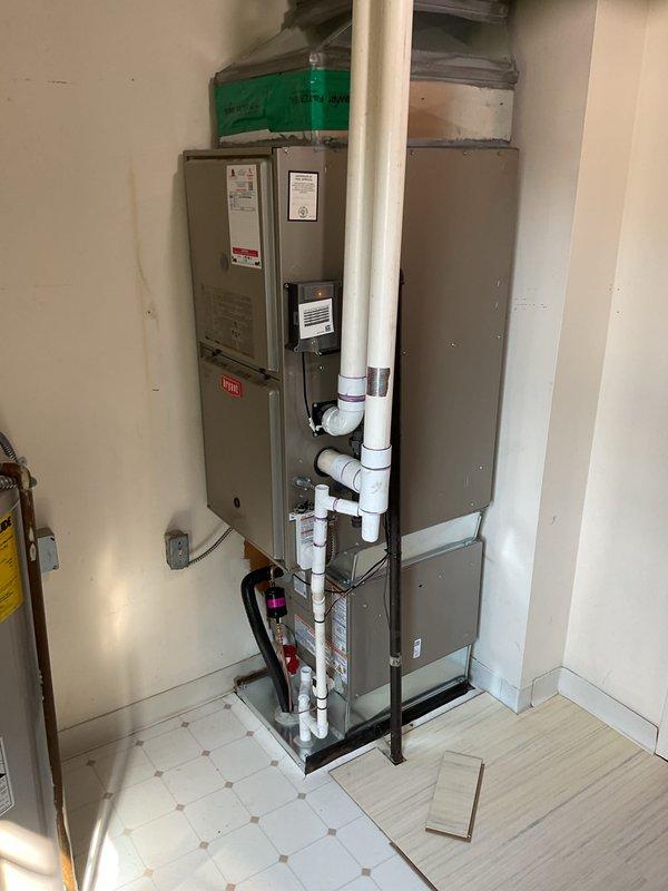 Completed installation of new air conditioning system including outdoor condensing unit and indoor evaporator coil. The outdoor unit was positioned on a protective pad against the building's exterior with proper clearances maintained for optimal airflow and service access. All refrigerant lines were properly connected and insulated, electrical connections were made to code specifications, and the condensate drainage system was installed and tested for proper operation. The indoor evaporator coil was integrated with the existing furnace system in the utility room, with all ductwork connections sealed and secured. System was charged with refrigerant to manufacturer specifications, startup procedures were completed, and full operational testing confirmed proper cooling performance and temperature differentials across the coil.