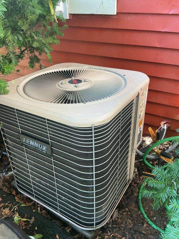 Performed comprehensive air conditioning tune-up on Lennox outdoor condensing unit as included maintenance with recent gas furnace installation. Completed full system inspection, recorded equipment model and serial number information from manufacturer data plate, verified proper operation of condenser fan motor and compressor, and documented unit condition with photographs showing installation location against building exterior with adequate clearance from surrounding vegetation.