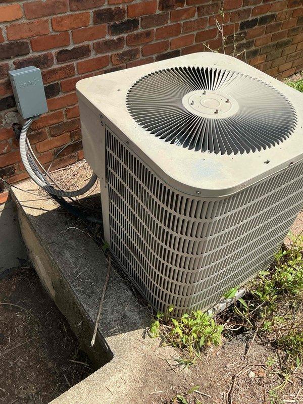 Completed installation of new air conditioning condenser unit and evaporator coil system. Unit was positioned on concrete pad adjacent to brick exterior wall with proper electrical disconnect and conduit installation per code requirements. All electrical connections were secured, refrigerant lines were installed and charged, and system was tested for proper operation and verified to be cooling effectively.