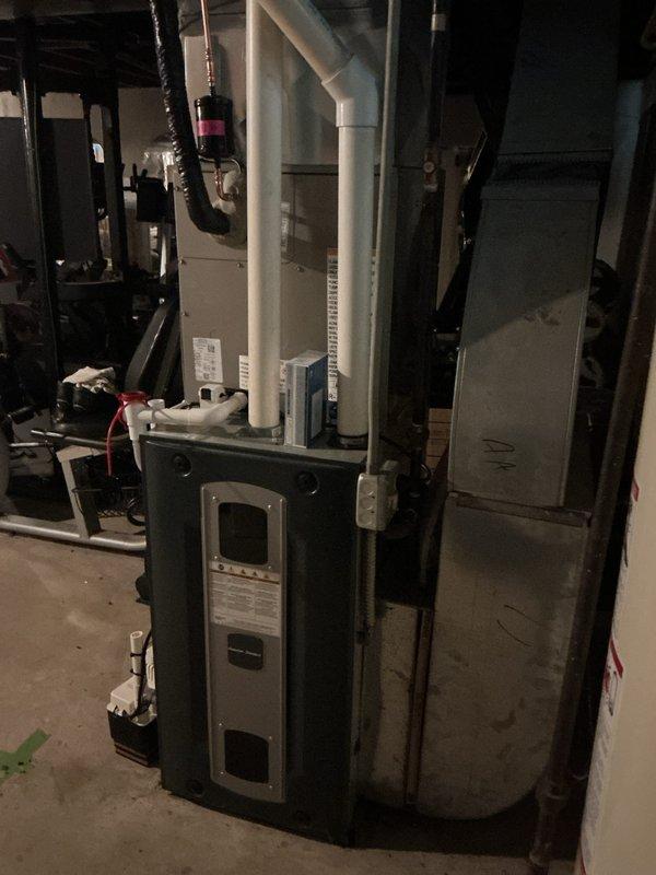 Completed installation of new air conditioning system with evaporator coil in residential basement mechanical room. System installed adjacent to existing furnace with proper refrigerant line connections, condensate drainage via PVC piping, electrical wiring to breaker panel, and integrated ductwork connections to existing HVAC infrastructure for optimal cooling performance.