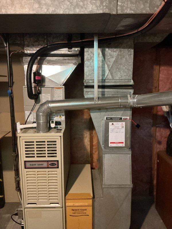 Completed full HVAC system installation including new air conditioning unit with matching evaporator coil integrated with existing Carrier furnace. Installed new ductwork with Y-junction fitting for proper airflow distribution, connected refrigerant lines using copper piping with shutoff valves, and integrated Space-Gard air cleaner for enhanced indoor air quality. All equipment properly mounted, connected, and tested for optimal performance with service financing documentation completed and identification verified on file.