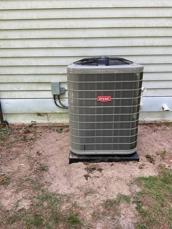 Completed full HVAC system installation including Bryant furnace, air conditioning condenser unit, and humidifier in basement utility area. Installed outdoor condenser on plastic pad against exterior wall with proper refrigerant line set penetration through siding and electrical disconnect box mounted adjacent to unit. Interior installation included furnace with integrated humidifier assembly, PVC venting system, condensate drain lines, and flexible ductwork connections. All equipment installed per manufacturer specifications with proper clearances and secured mounting. System tested and operational upon completion.