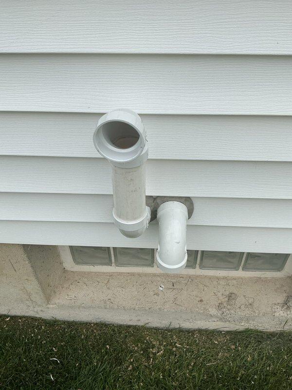 Completed HVAC system installation with proper exterior PVC venting configuration installed through building foundation and extending vertically along exterior wall. New water heater installed in basement utility area with appropriate black flex connector piping and secure metal clamp connections. Follow-up visit scheduled to address remaining punch list items to finalize installation warranty work.