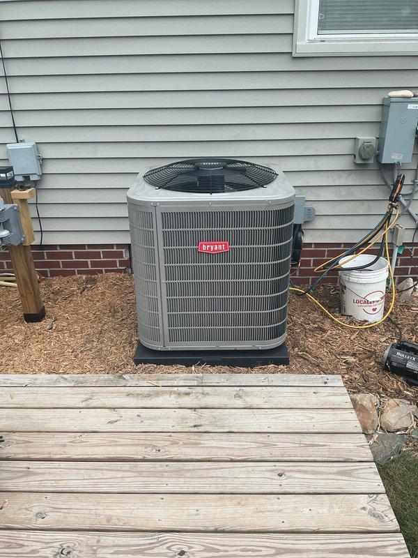 Completed installation of new Bryant air conditioning system including outdoor condensing unit and indoor evaporator coil. Unit was positioned on concrete pad against exterior wall with proper clearances, refrigerant lines were run and connected to disconnect box, and all electrical connections were completed per manufacturer specifications. Indoor coil was installed in utility room with proper drainage and refrigerant line connections, system was charged, tested, and verified operational.