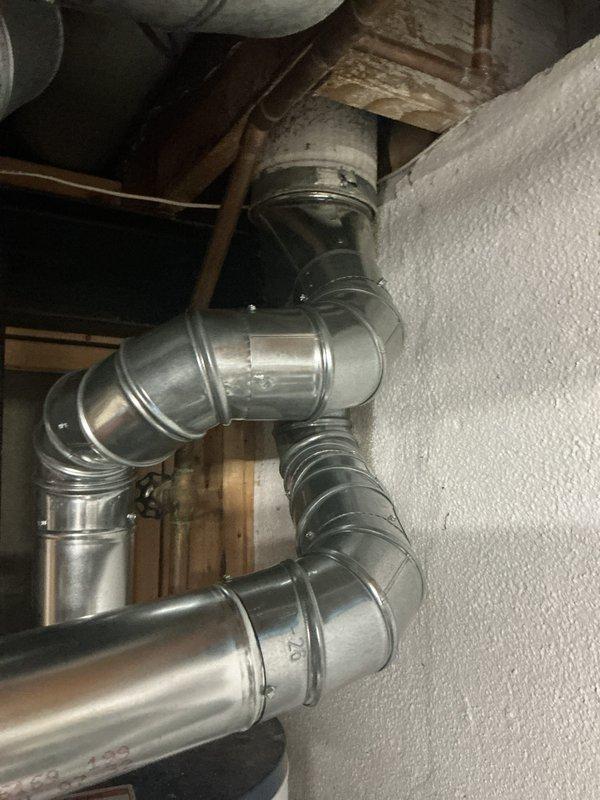 Completed full HVAC system installation including new furnace and air conditioning unit in residential basement utility area. Installed beige vertical furnace unit with proper venting using PVC piping secured with appropriate fasteners, connected flexible metallic ductwork to distribution system, and ensured proper condensate drainage lines were in place. Fabricated and installed custom galvanized metal ductwork throughout attic space, including multiple elbow configurations and T-junction connections to optimize airflow distribution, with all seams properly crimped and sealed for efficient operation.