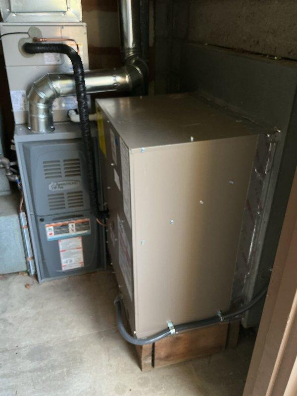 Completed installation of new air conditioning system with evaporator coil in basement utility area. Installed air handler unit with corresponding ductwork connections, integrated with existing furnace system using proper metallic ductwork and flexible conduit. Established new venting system with rigid metal flue pipe through foundation wall, secured all components to wooden platform base, and verified proper clearances per manufacturer specifications.
