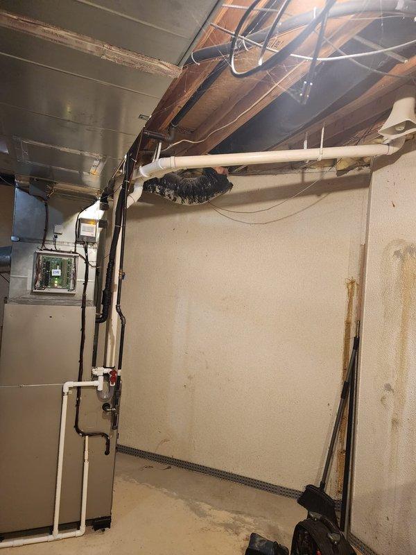 Completed full HVAC system installation including new furnace, air conditioner, and humidifier in basement utility area. Installed and secured all ductwork connections, PVC condensate drain lines with proper pitch and support brackets, refrigerant lines, and electrical connections per manufacturer specifications. Routed condensate piping through ceiling penetration with appropriate sealing, mounted all equipment on level surface, and verified proper clearances for service access and code compliance.