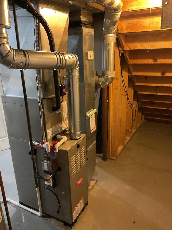 Completed full HVAC system installation including gas furnace, central air conditioning condenser unit, and whole-home humidifier in residential basement mechanical room. Installed Bryant brand outdoor condensing unit on composite pad against exterior foundation with proper clearances, mounted electrical disconnect box on exterior siding, and ran refrigerant line set and electrical conduit from disconnect to unit. Interior installation included vertical gas furnace with supply and return ductwork connections, integrated humidifier system, and all necessary electrical wiring and control connections. All equipment properly vented, leveled, and tested for operation. System commissioned and verified for proper airflow, refrigerant charge, and humidity control functionality.