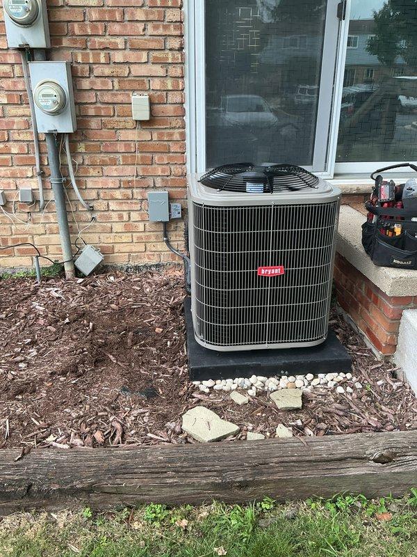 Completed installation of new residential air conditioning system including outdoor condensing unit and indoor evaporator coil. Positioned outdoor unit on level pad against exterior brick wall with proper clearances for airflow and service access. Installed refrigerant line set with insulation connecting outdoor condenser to indoor coil mounted above existing furnace in basement utility area. Established electrical connections to outdoor unit utilizing existing meter base and disconnects mounted on exterior wall. Integrated evaporator coil into existing ductwork system with proper condensate drainage using PVC piping with trap configuration. Verified all refrigerant connections are secure and system is charged to manufacturer specifications. Tested system operation including compressor function, airflow, and temperature differential across coil. System operating within normal parameters and cooling effectively.