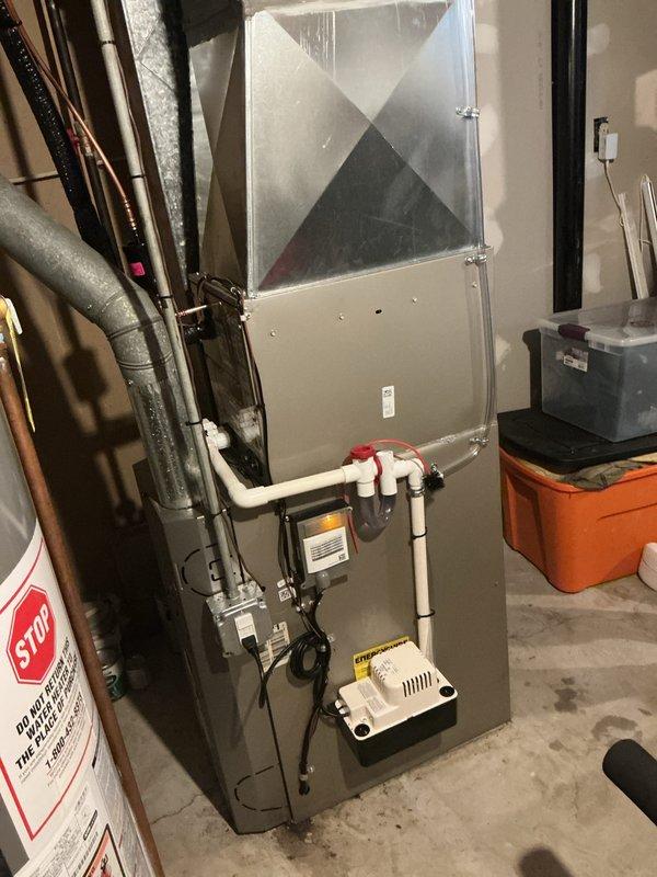 Completed installation of new residential air conditioning system including outdoor condensing unit and indoor evaporator coil. Positioned outdoor unit on level pad against exterior brick wall with proper clearances for airflow and service access. Installed refrigerant line set with insulation connecting outdoor condenser to indoor coil mounted above existing furnace in basement utility area. Established electrical connections to outdoor unit utilizing existing meter base and disconnects mounted on exterior wall. Integrated evaporator coil into existing ductwork system with proper condensate drainage using PVC piping with trap configuration. Verified all refrigerant connections are secure and system is charged to manufacturer specifications. Tested system operation including compressor function, airflow, and temperature differential across coil. System operating within normal parameters and cooling effectively.