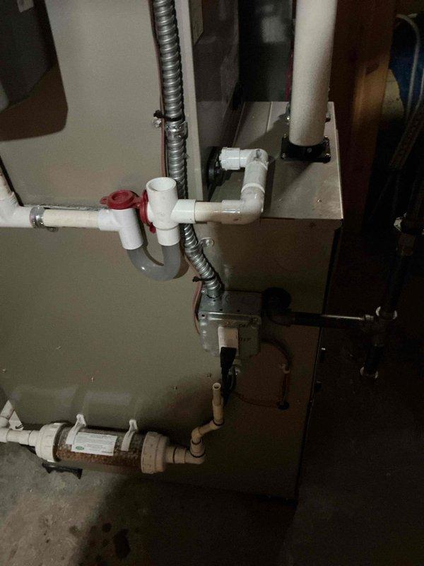 Completed installation of Honeywell IAQ thermostat backplate on Bryant HVAC system. Verified proper mounting and connections to existing furnace/air handler unit with associated PVC condensate drainage and venting system. System operational and warranty service fulfilled.