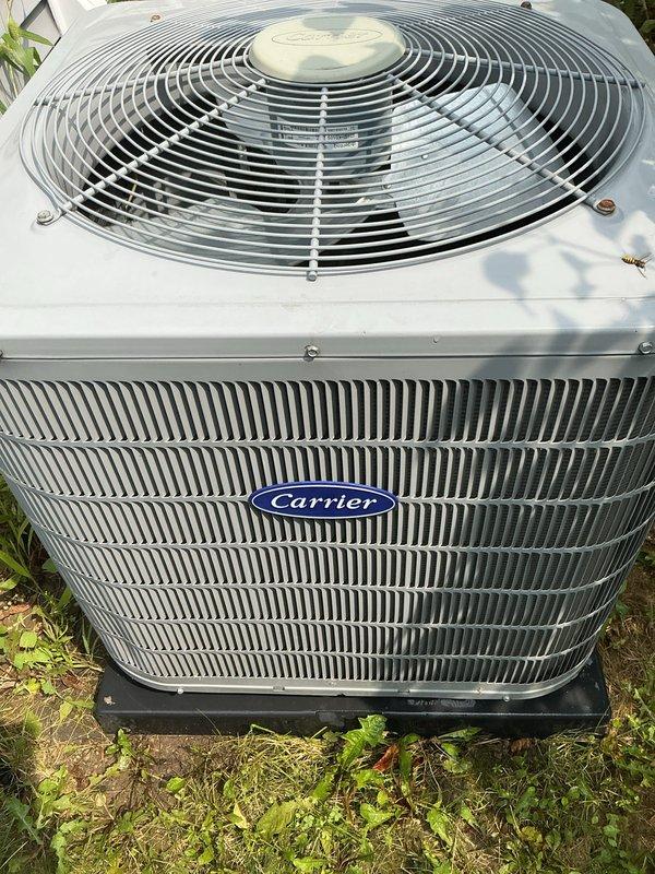 Performed comprehensive AC tune-up on aging outdoor Carrier condensing unit. Completed full system inspection including examination of condenser coils, fan assembly, and electrical components. Unit showed normal wear consistent with age but was operating within acceptable parameters. Cleaned and inspected louvered panels, verified proper airflow through heat exchange fins, and checked fan grille assembly for secure mounting. All fasteners and housing components were found to be properly secured with no visible damage or deterioration noted. System operational upon completion of maintenance service.