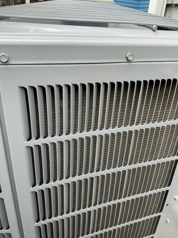 Performed comprehensive AC tune-up on aging outdoor Carrier condensing unit. Completed full system inspection including examination of condenser coils, fan assembly, and electrical components. Unit showed normal wear consistent with age but was operating within acceptable parameters. Cleaned and inspected louvered panels, verified proper airflow through heat exchange fins, and checked fan grille assembly for secure mounting. All fasteners and housing components were found to be properly secured with no visible damage or deterioration noted. System operational upon completion of maintenance service.
