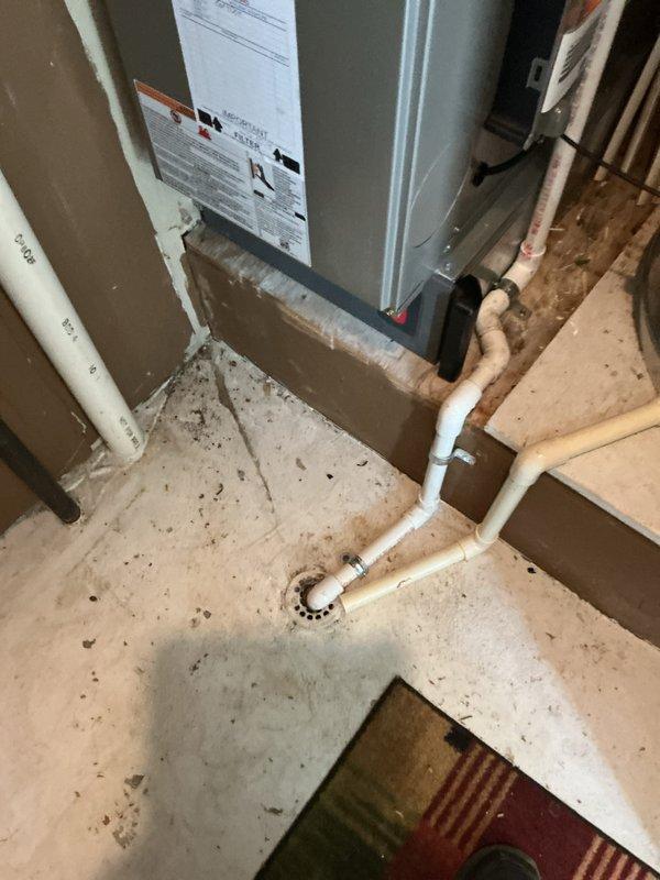 Completed installation of new air conditioning system with evaporator coil in residential utility space. System includes new air handler unit integrated with existing furnace, with all refrigerant lines, condensate drainage via PVC piping to floor drain, and electrical connections properly configured. All equipment tested and operational, with manufacturer labels and safety documentation visible and intact per code requirements.