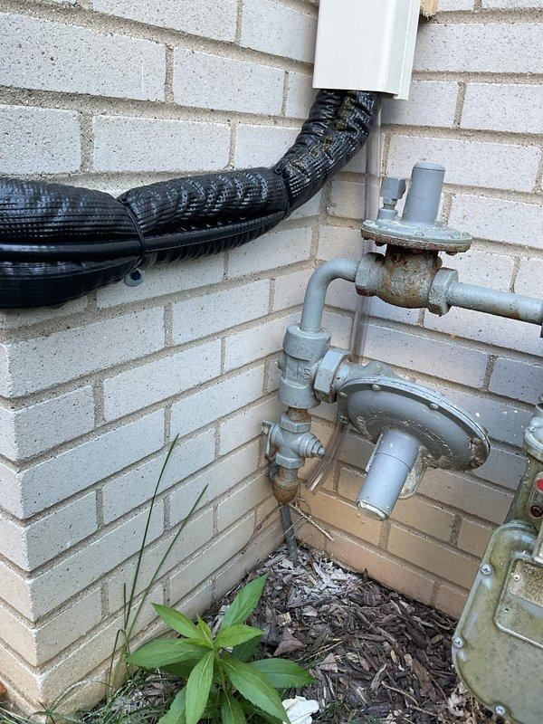 Completed installation of ductless mini-split heat pump system in residential bedroom. Mounted indoor air handler unit on interior wall with proper clearances between two windows, installed outdoor condenser unit on exterior brick wall with secure mounting and proper refrigerant line routing through black flexible conduit, and tested system operation to verify proper heating and cooling functionality.